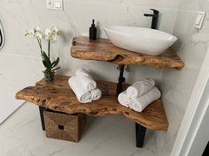 a bathroom with two wooden shelves holding towels and a white bowl on the sink counter