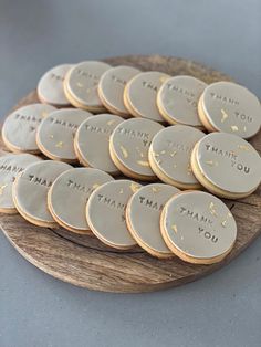 some cookies that are sitting on a wooden platter with the words thank you written on them