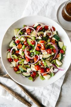 a white bowl filled with salad next to a cup of tea and utensils