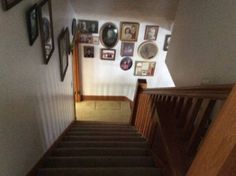 stairs with pictures on the wall and framed photos on the wall above them, along with wooden banisters