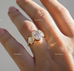 a woman's hand with a diamond ring on top of her finger and two diamonds in the middle