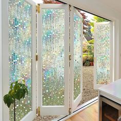 an open glass door with beads on it in front of a white table and window