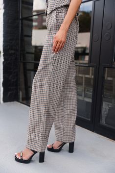 Make a statement in the Sophia Brown & Black Houndstooth Pants. Designed with a classic cream, black, and brown houndstooth print, these wide-leg pants offer both comfort and sophistication. Featuring a front button-up with zipper closure, belt loops, and functional front pockets, they combine practicality with style. Pair them with the matching Sophia Vest for a bold, coordinated outfit, or mix and match with your favorite tops for a variety of looks. Classic Houndstooth Pants For Business Casual, Brown Ankle-length Wide Leg Pants For Work, Brown Wide Leg Ankle-length Workwear Pants, Chic Plaid Wide Leg Pants, Tailored Houndstooth Bottoms For Fall, Business Casual Houndstooth Tapered Leg Bottoms, Tapered Leg Houndstooth Bottoms For Business Casual, Plaid Wide Leg Pants For Business Casual, Tapered Leg Houndstooth Pattern Bottoms For Business Casual