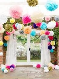 colorful paper flowers and pom poms decorate the entrance to an outdoor wedding venue