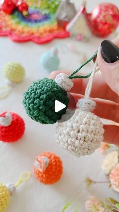 crocheted ornaments are being held up by someone's hand on a table