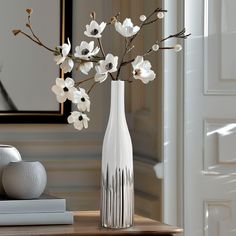 a white vase filled with flowers sitting on top of a table next to a book