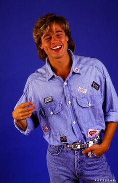 a man in blue shirt and jeans posing for the camera with his hand on his hip