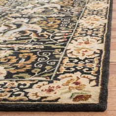 a black and beige rug on the floor with wood floors in the background, close up