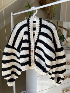 a black and white striped sweater hanging on a clothes rack