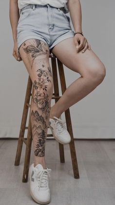 a woman sitting on top of a wooden chair with tattoos on her leg and legs