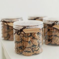 three jars filled with cookies sitting on top of a white counter next to each other