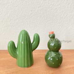 a green cactus sitting next to a small ceramic cactus