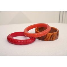 This is part of Chairish’s Costume Jewelry assortment.  The set of 3 art deco vintage authentic carved bangle bakelite bracelets are in the hues of red, amber orange and caramel. They are all hand carved and the orange caramel one is a thicker cuff with small swirls of black. The caramel on is 1.25" H x 3" W and the interior of that one is approx. 2.5" W. The other two are .5" H x 3.5" W and the other of those are 2.5" W. They will fit over a small medium wrist or medium wrist but not an extra w Vintage Red Round Bangle, Handmade Bakelite Bangle Bracelet, Handmade Bakelite Bracelets As Gift, Vintage Carved Orange Jewelry, Elegant Bakelite Bracelets For Gift, Elegant Bakelite Bracelets As A Gift, Elegant Bakelite Bangle As Gift, Vintage Orange Carved Jewelry, Elegant Bakelite Bangle As A Gift