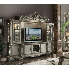 an ornate entertainment center with mirrored doors and silver furniture in a living room, including a large television