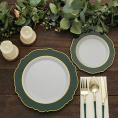 the place setting is set with green and white plates, silverware, and greenery