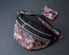 a multicolored floral print fanny bag with matching wallet and keychain on a black surface