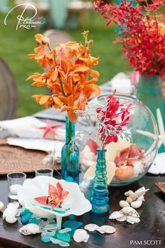 there are flowers in vases and seashells on the table with other items