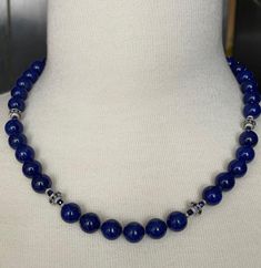 This gorgeous necklace of round lapis lazuli beads with sapphire and white gold accents is the epitome of style and sophistication! 10mm round, beautifully matched lapis with their high-polish and stunning royal blue color have been arranged with 18k white gold rondels, faceted blue sapphire beads and white gold rondels. The larger white gold rondels are set with tiny sparkling sapphires that complement the lapis perfectly, and the white gold accents have a lovely stardust finish, treating your eyes to a wonderful combination of sizes, shapes, color and textures. Hand strung on silk thread and finished with a 14k white gold clasp, this necklace is a great way to show off your sense of style and that undefinable look of understated, effortless elegance! Necklace measures 19 inches in length Elegant Lapis Lazuli Necklace With Polished Beads, Elegant Blue Necklace With 8mm Beads, Elegant Blue Necklaces With 8mm Beads, Royal Blue Lapis Lazuli Necklaces With Round Beads, Elegant Beaded Necklaces With Round Lapis Lazuli Beads, Luxury Blue Beaded Necklace With Polished Beads, Royal Blue Lapis Lazuli Necklace With Round Beads, Elegant Lapis Lazuli Beaded Necklaces With Round Beads, Elegant Lapis Lazuli Beaded Necklace With Round Beads