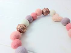 a close up of a necklace made out of felt beads and glitter balls on a white table