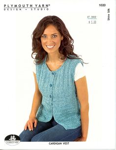 a woman sitting on the ground wearing a blue vest