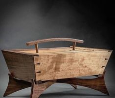 a wooden box sitting on top of a black table next to a knife holder in the shape of a boat