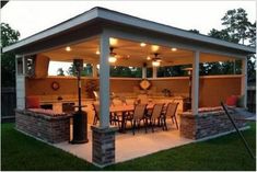 an outdoor kitchen and dining area is lit up at night with lights on the ceiling