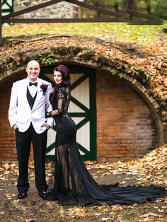 a man and woman dressed up in formal wear posing for a photo outside an old brick building