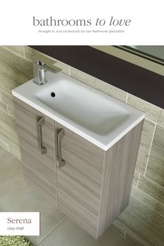 a bathroom sink sitting under a mirror next to a wall mounted faucet in front of a tiled wall