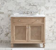 a bathroom vanity with marble top and two drawers on one side, and a white rug on the other