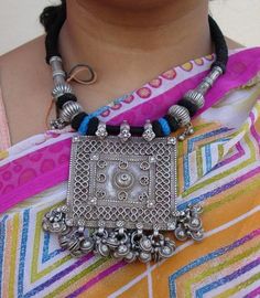 "Antique Tribal old silver necklace from Rajasthan India. These necklaces worn by Banjara tribal people from Rajasthan Desert. One big size heavy square old silver pendant re strung together strongly with four old silver beads ,end finish with loop and silver ball. Attached noisy bells in all the bottom loops. The middle big pendant called (silver house amulet) a symbol of family unity represented by walled-in rectangle, the amulet uses stamped floral units to cover joins. See similar sample in Rajasthan Desert, Family Unity, Big Pendant, Silver Necklace Pendant, Traditional Jewellery, Jewellery Inspiration, Rajasthan India, Boho Vintage, Traditional Jewelry