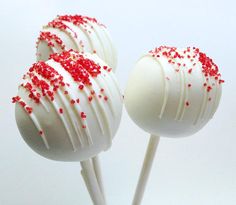 two white cake pops with red sprinkles on them, one is larger than the other