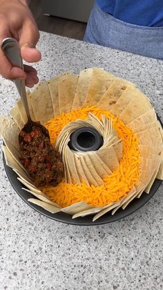 a person is cutting into some food on a plate with cheese and meat in it