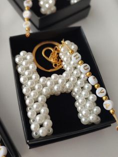 pearls and gold beads are arranged in the shape of a letter on a black box