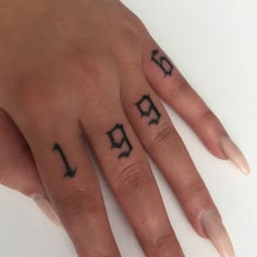 a woman's hand with two fingers and numbers tattooed on the thumbnails