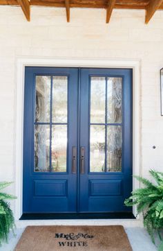 a blue front door with two sidelights and a welcome mat on the ground in front of it