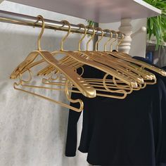 gold clothes hangers are hanging on a white wall next to a potted plant