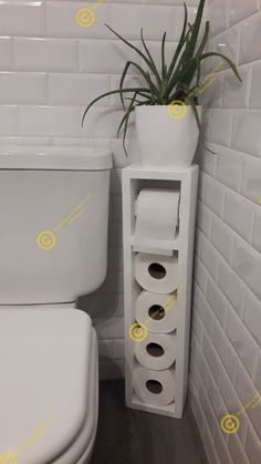 a white toilet sitting next to a tall plant in a bathroom with yellow stickers on the wall