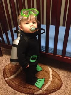 a young boy wearing scuba gear and goggles standing in front of a crib