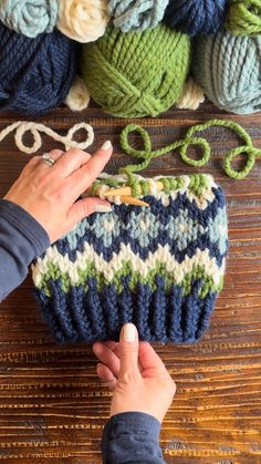 someone is knitting something on the table with yarn and crochet hooks in front of them