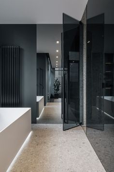 an empty bathroom with black walls and white bathtub in the center, along with large glass partitions