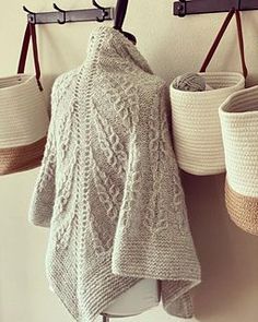 three baskets are hanging on the wall next to a coat rack and two sweaters