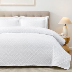 a bed with white comforter and pillows in a bedroom