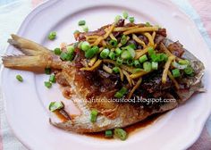 a white plate topped with fish covered in sauce and green onions