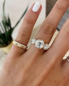 a woman's hand with three different rings on her fingers and one ring in the middle