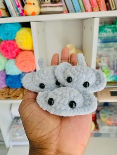 someone is holding up some small crocheted animal faces in front of a book shelf