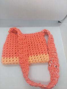 an orange crocheted purse sitting on top of a white box