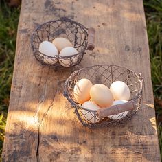 two baskets filled with eggs sitting on top of a wooden table