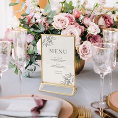 a table set for a formal dinner with pink flowers and gold place settings on it