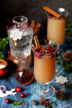 two glasses filled with drinks sitting on top of a blue table covered in christmas decorations