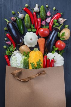 a brown paper bag filled with lots of different types of vegetables and veggies